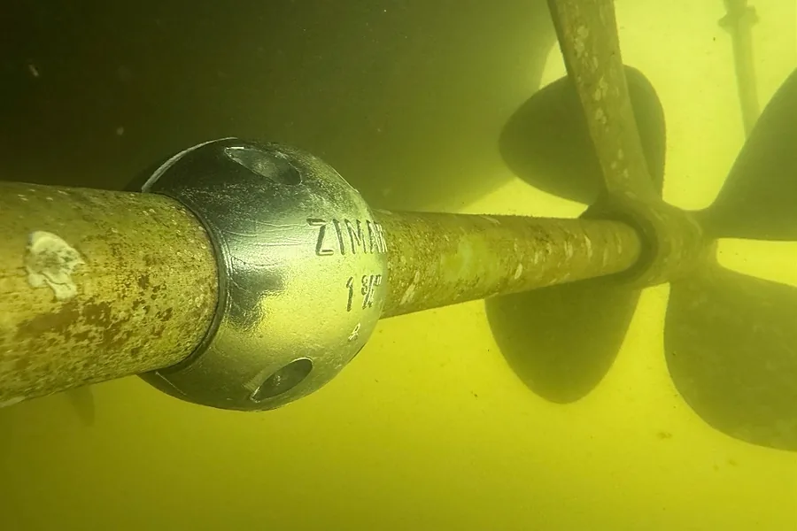 Ánodo de zinc de la marca ZIMAR montado sobre el eje de una embarcación bajo el agua, con la hélice al fondo.